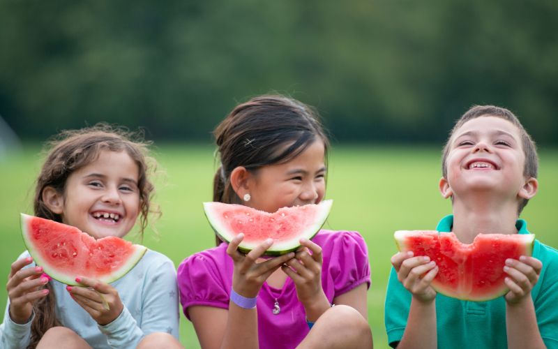 Kinder im Waldkindergarten die ihre Melonen genießen