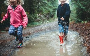 Kinder im Waldkindergarten die durch ein Pfütze laufen