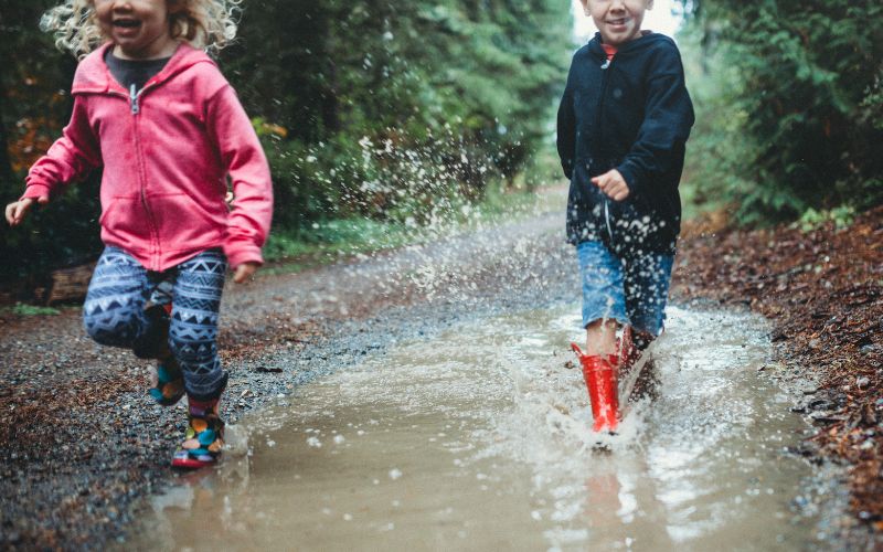 Kinder im Waldkindergarten die durch ein Pfütze laufen