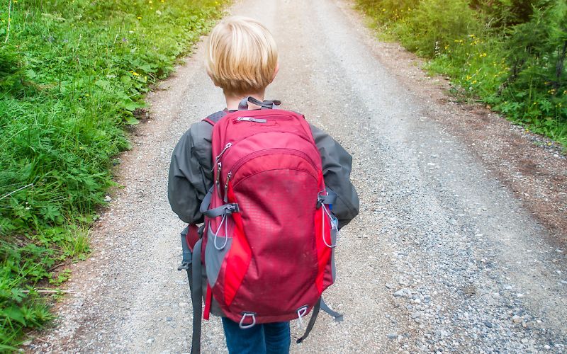 Kind läuft in den Wald im Waldkindergarten