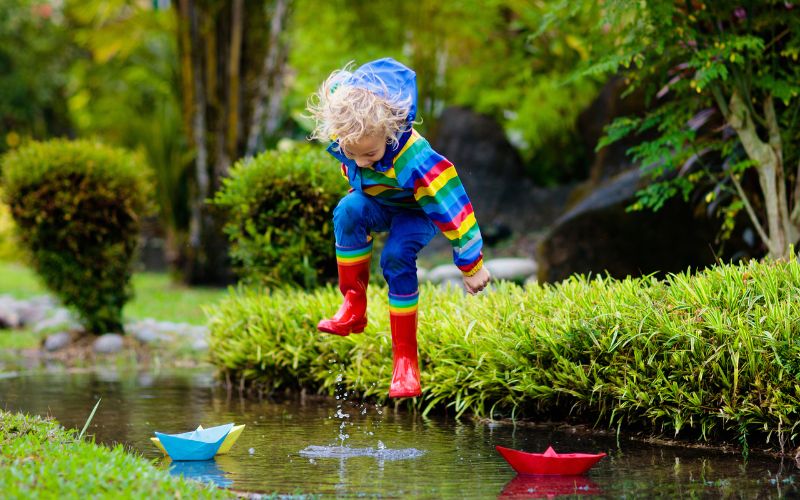 Kind im Waldkindergarten springt in Pfütze
