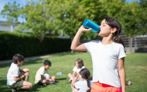 Mädchen trinkt aus Trinkflasche im Waldkindergarten