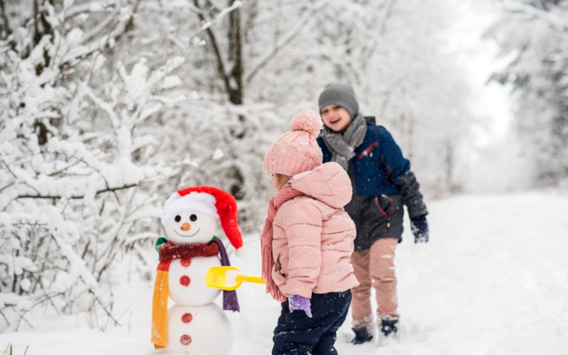 Kinder beim Spielen im Schnee im Waldkindergarten
